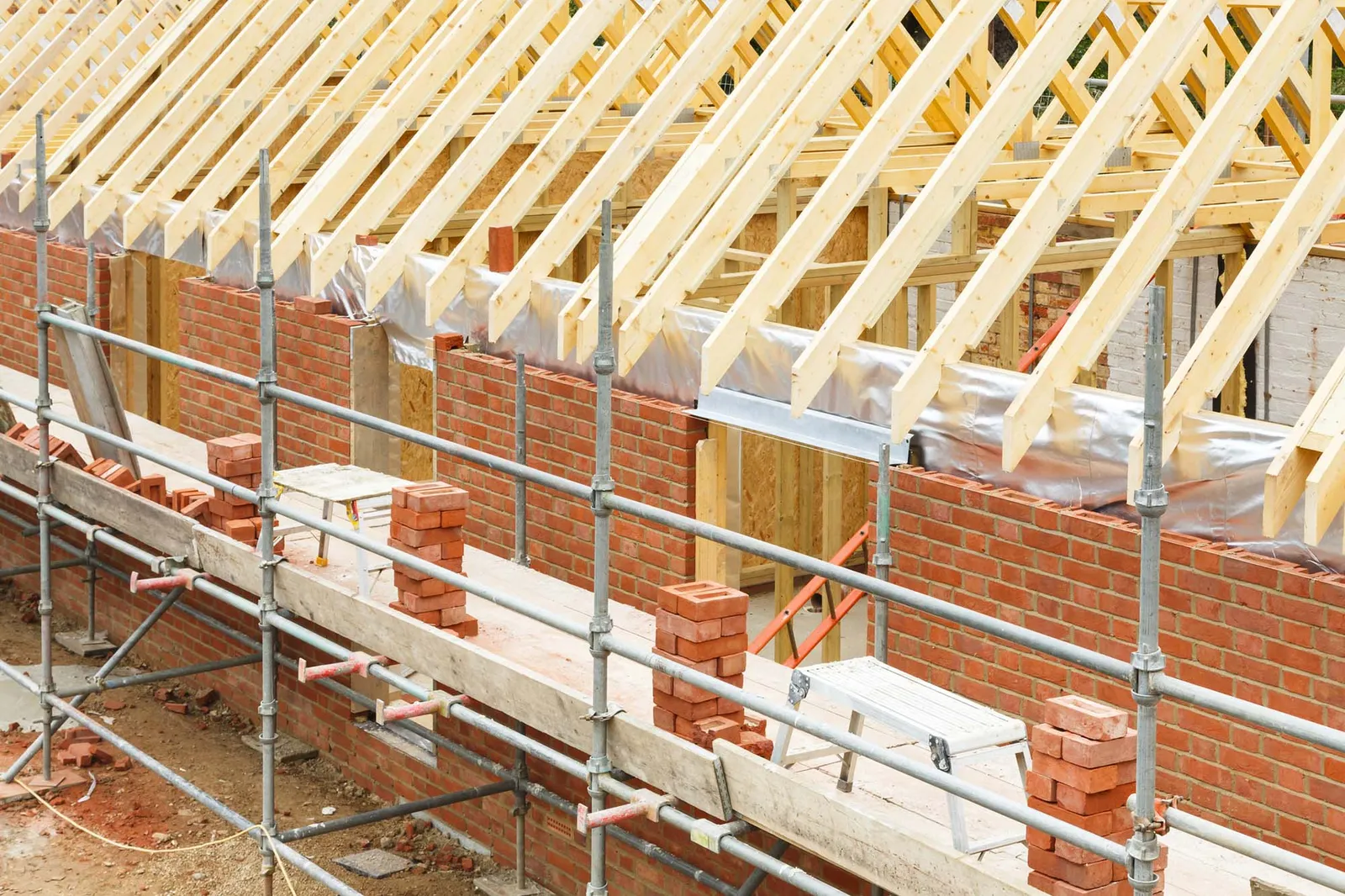 Houseing in the process of being built with brick and wood roofing